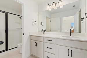 Bathroom featuring tile patterned flooring, vanity, toilet, and a shower with shower door