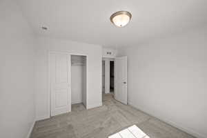 Unfurnished bedroom with light colored carpet and a closet