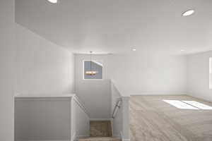 Staircase featuring a chandelier and carpet flooring