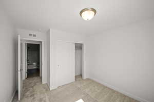 Unfurnished bedroom featuring a closet and light colored carpet