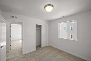 Unfurnished bedroom featuring light carpet and a closet