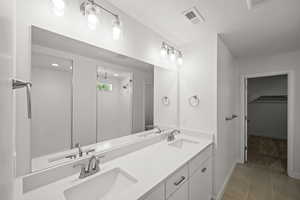 Bathroom featuring tile patterned flooring, vanity, and walk in shower