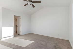 Unfurnished room featuring ceiling fan, light colored carpet, and vaulted ceiling