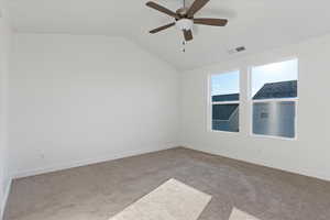 Spare room featuring light colored carpet, vaulted ceiling, and ceiling fan