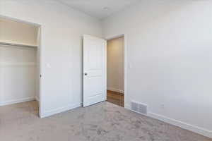 Unfurnished bedroom featuring light carpet and a closet