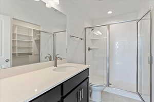 Bathroom featuring toilet, tile patterned flooring, vanity, and walk in shower