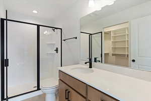 Bathroom featuring tile patterned flooring, vanity, toilet, and a shower with door