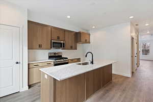 Kitchen featuring sink, an island with sink, stainless steel appliances, and light hardwood / wood-style floors