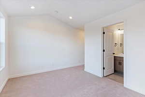 Carpeted empty room with lofted ceiling