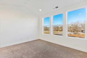 Carpeted spare room with vaulted ceiling