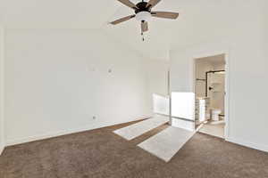 Carpeted empty room with ceiling fan and vaulted ceiling