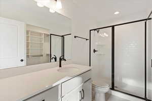 Bathroom with tile patterned floors, vanity, toilet, and a shower with door