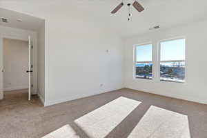 Carpeted spare room featuring ceiling fan and lofted ceiling