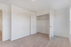 Unfurnished bedroom featuring light carpet and a closet