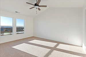 Empty room featuring carpet floors, vaulted ceiling, and ceiling fan