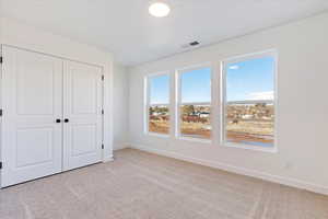 Unfurnished bedroom with light carpet and a closet