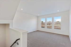 Carpeted spare room with lofted ceiling