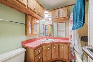 Full bathroom featuring vanity, shower / bathtub combination with curtain, a textured ceiling, and toilet