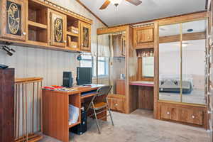 Carpeted office with ceiling fan, lofted ceiling, and a textured ceiling