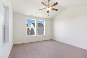 Carpeted spare room with ceiling fan and vaulted ceiling