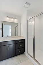 Bathroom with tile patterned flooring, vanity, and a shower with door