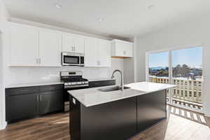 Kitchen with a kitchen island with sink, sink, white cabinets, and stainless steel appliances