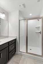 Bathroom with tile patterned flooring, vanity, and an enclosed shower