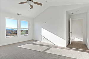 Unfurnished room with dark colored carpet, ceiling fan, and lofted ceiling