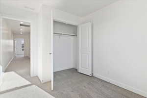 Unfurnished bedroom with light carpet and a closet