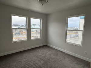 Empty room featuring a textured ceiling and carpet floors