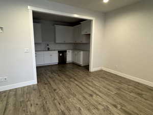 Kitchen with decorative backsplash, dark wood-type flooring, sink, dishwasher, and white cabinets