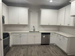 Kitchen featuring sink, white cabinetry, stainless steel appliances, and dark wood-type flooring