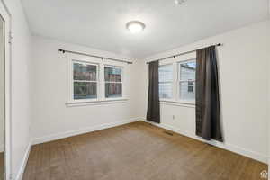 Unfurnished room featuring a textured ceiling and carpet floors