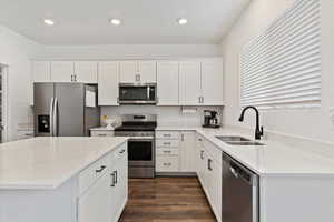 Kitchen with dark hardwood / wood-style floors, white cabinetry, sink, and appliances with stainless steel finishes