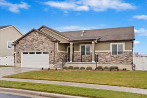 View of front of property featuring a front lawn, covered porch, and a garage