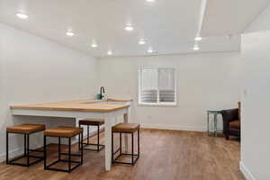 Kitchen with a breakfast bar, wooden counters, sink, light hardwood / wood-style flooring, and kitchen peninsula