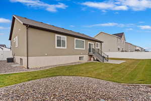 Rear view of property featuring a lawn and central air condition unit