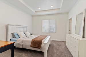 Carpeted bedroom featuring a tray ceiling