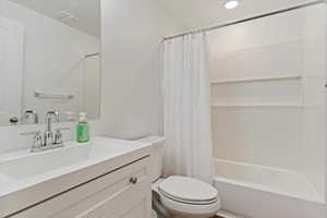 Full bathroom featuring shower / bath combination with curtain, vanity, and toilet