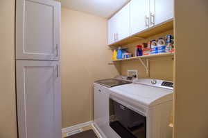 Laundry room featuring washing machine and dryer, cabinets, and a textured ceiling