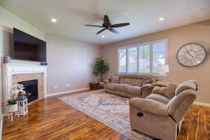 Living room with a textured ceiling, dark hardwood / wood-style floors, and ceiling fan