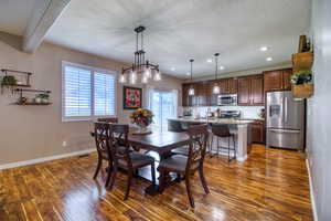 Dining room with beam ceiling, a textured ceiling, dark hardwood / wood-style floors, and sink