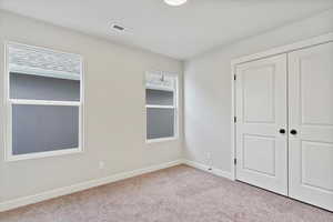 Unfurnished bedroom with light colored carpet and a closet