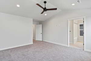 Unfurnished bedroom with lofted ceiling, light colored carpet, ceiling fan, and ensuite bathroom