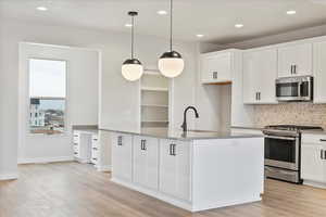 Kitchen featuring white cabinetry, appliances with stainless steel finishes, sink, and pendant lighting