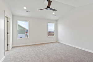 Empty room with light carpet, plenty of natural light, ceiling fan, and vaulted ceiling