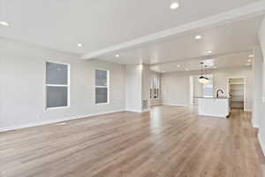 Unfurnished living room featuring sink, beam ceiling, a textured ceiling, and light wood-type flooring