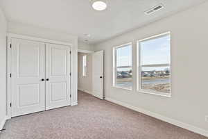 Unfurnished bedroom with light carpet and a closet