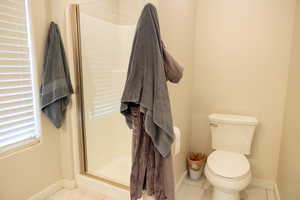 Master Bathroom featuring toilet, tile patterned floors, and a shower with door