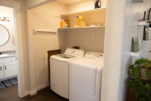 Laundry area with dark wood-type flooring, sink, and washing machine and clothes dryer